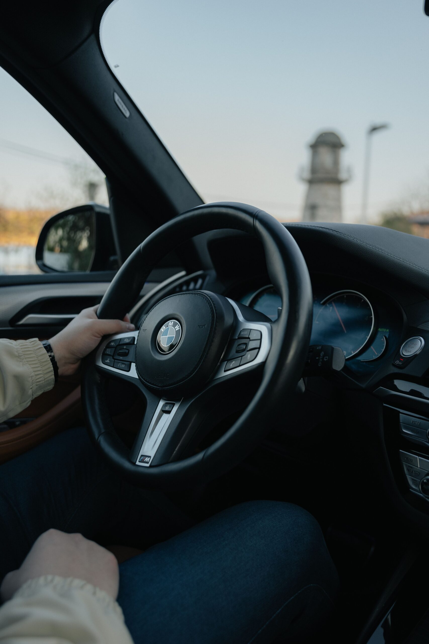 Close-up of a driver's hands clasping a car steering wheel, showcasing the elegant interior design.
