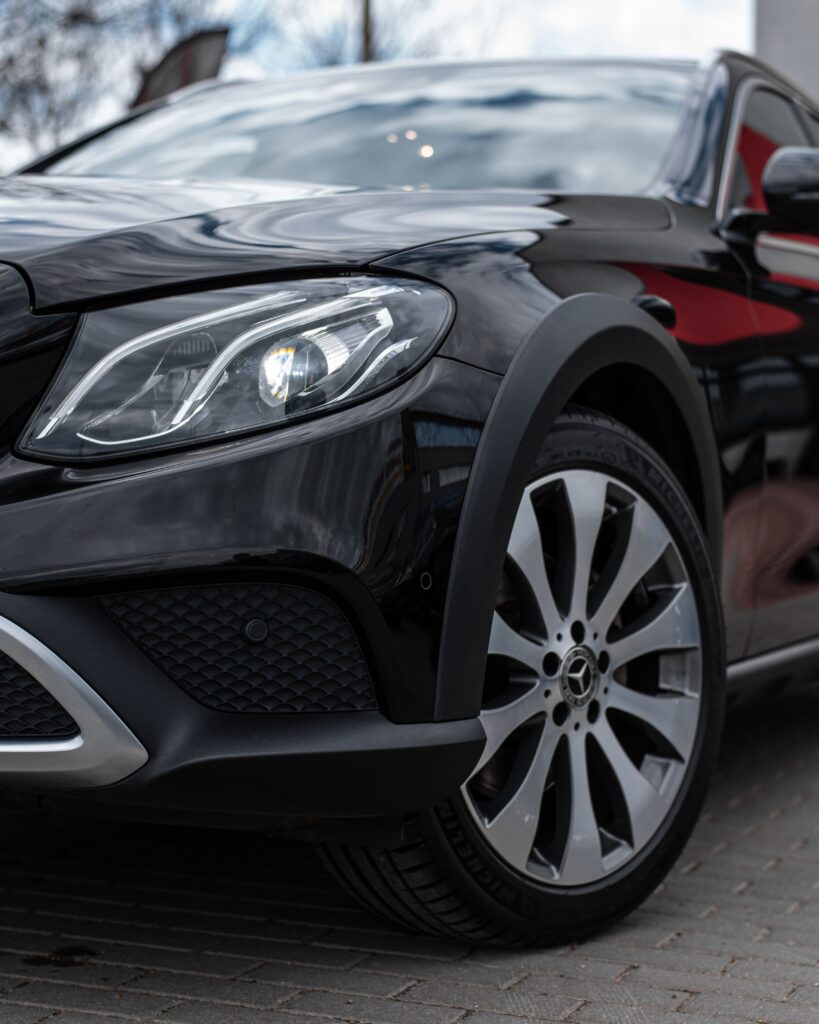 Detailed close-up of a luxury black sedan featuring a prominent headlight and sleek design.